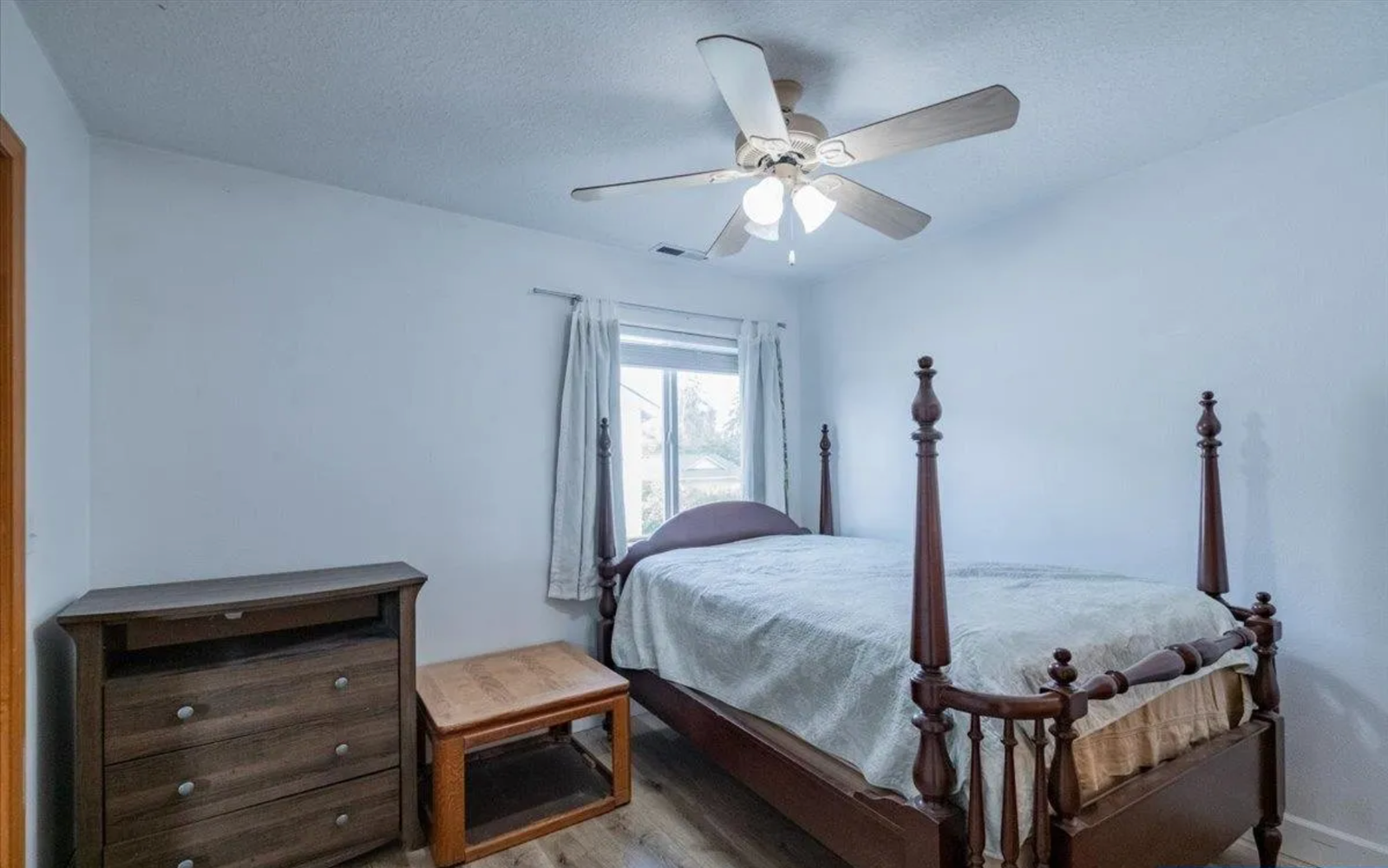 Guest bedroom before redesign, with dark wood four-poster bed